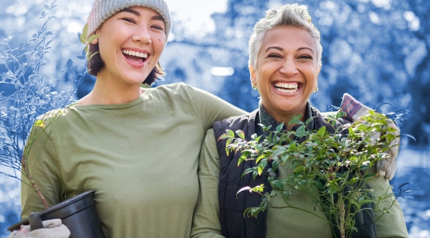 two smiling women holding potted plants